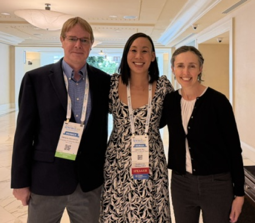 Three conference attendees smiling together in a hotel corridor