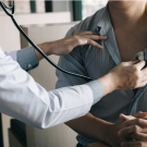 Doctoer using stethoscope on patient to listen to chest