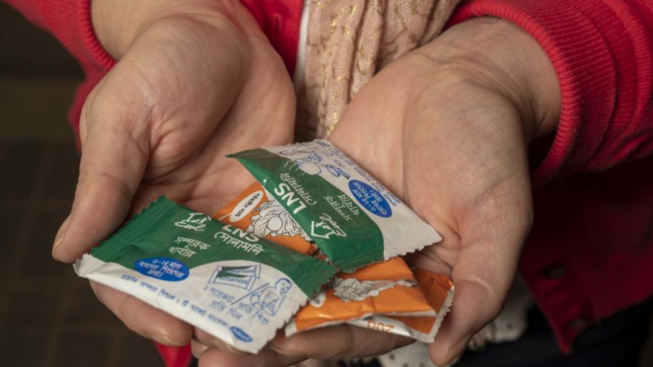 Christine Stewart holds packets of nutrient supplements. They are typically a mixture of a legume — peanut, lentil or chickpea paste — plus milk powder, oil, and a full complement of the vitamins and minerals children need. (Karin Higgins/UC Davis)