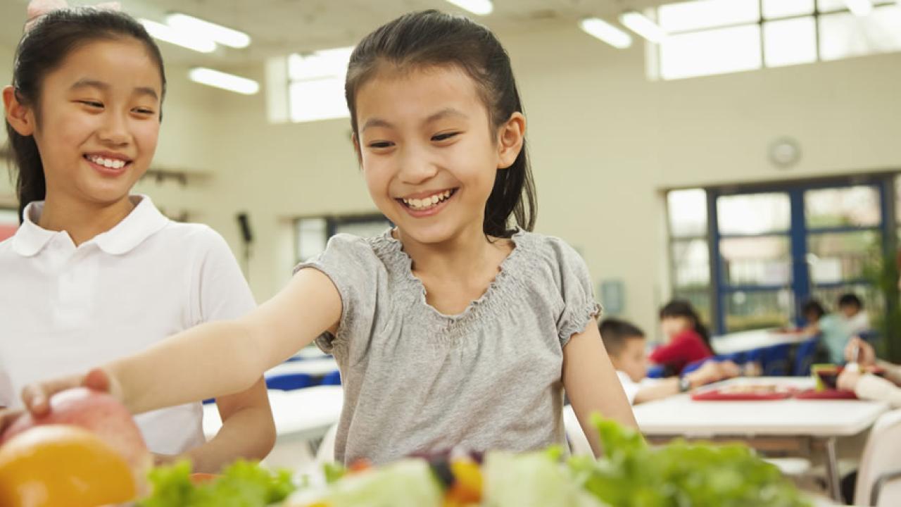 Two kids, one grabbing for fruits