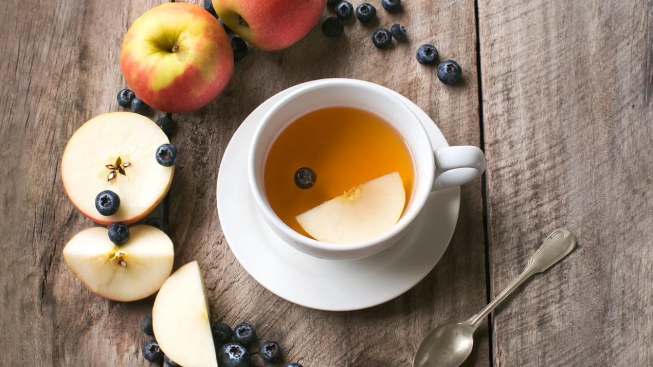 Image of a cup of tea with apples and berries around it